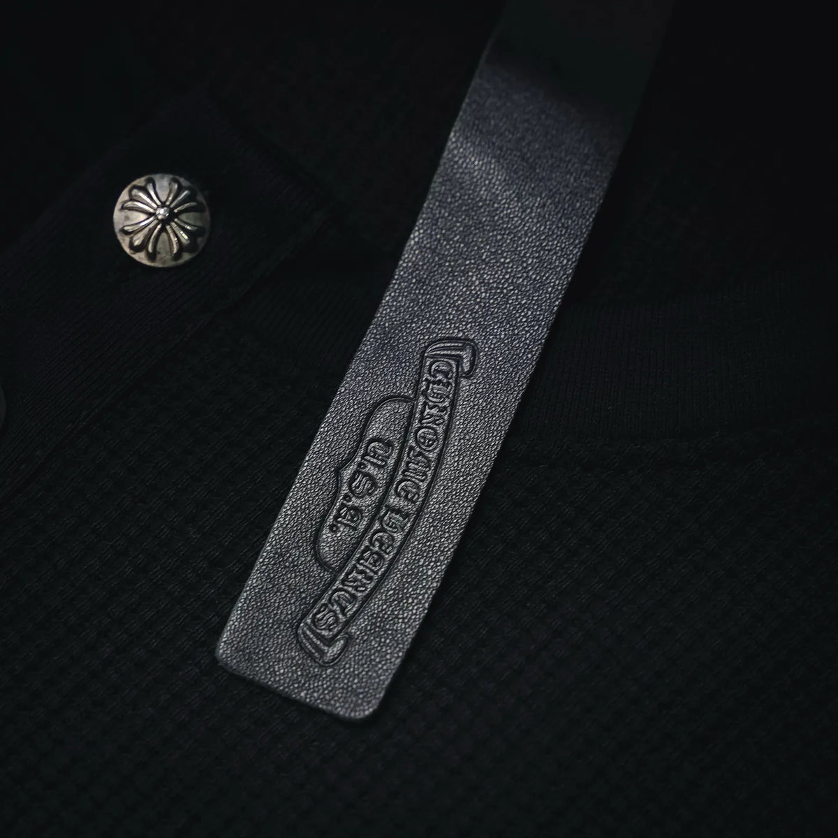 Leather-look hem label with embossed logo text on dark henley