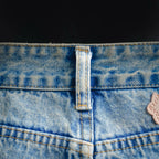 Light blue denim waist with button closure and stitched fly seam close-up