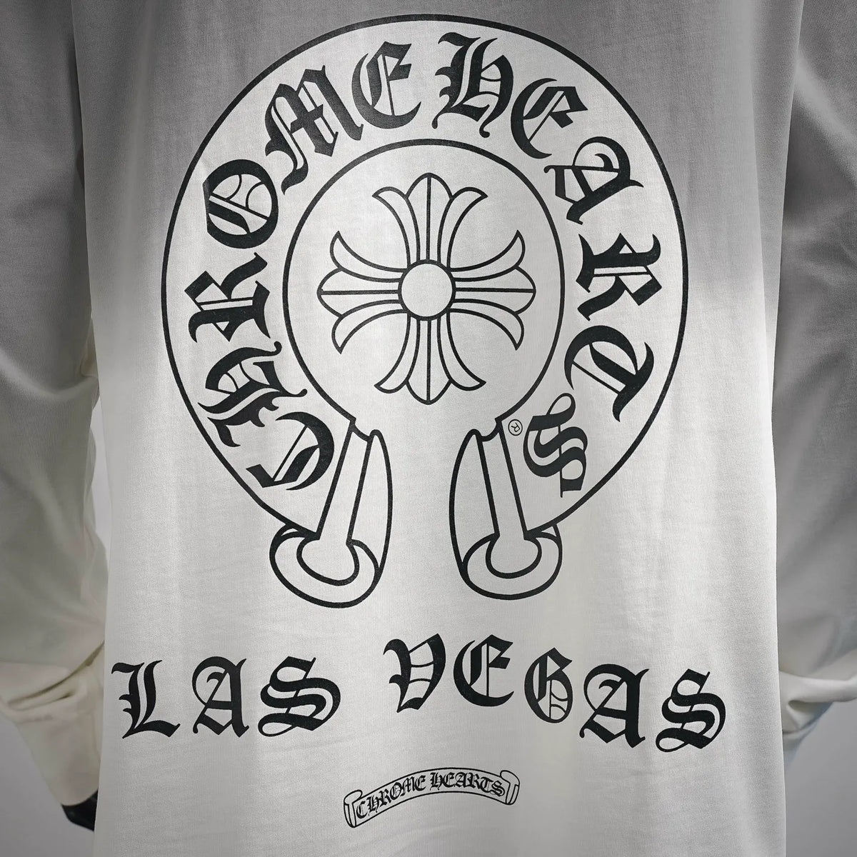 White long-sleeve T-shirt with large circular flower graphic and arched lettering