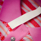 Close-up of polo neckline label and pink placket seam at inner collar