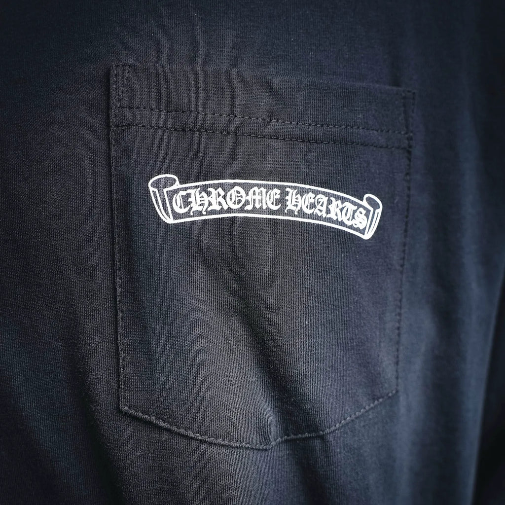 Dark long-sleeve shirt with chest pocket and white Chrome Hearts logo badge.