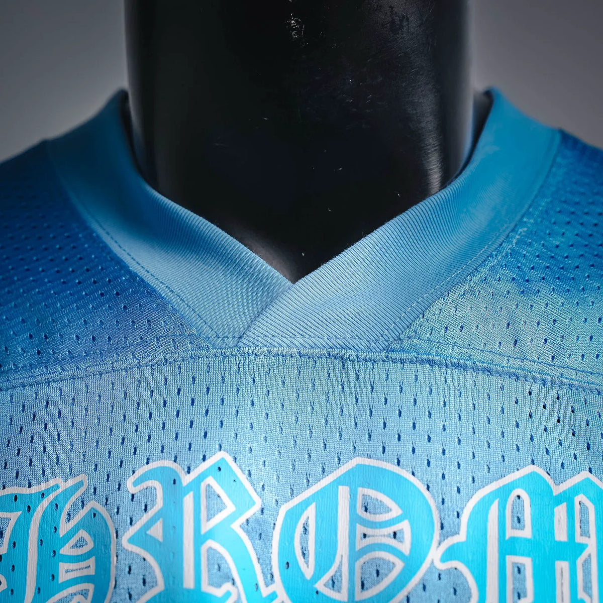 Close-up of light blue jersey neckline and lower front lettering graphic