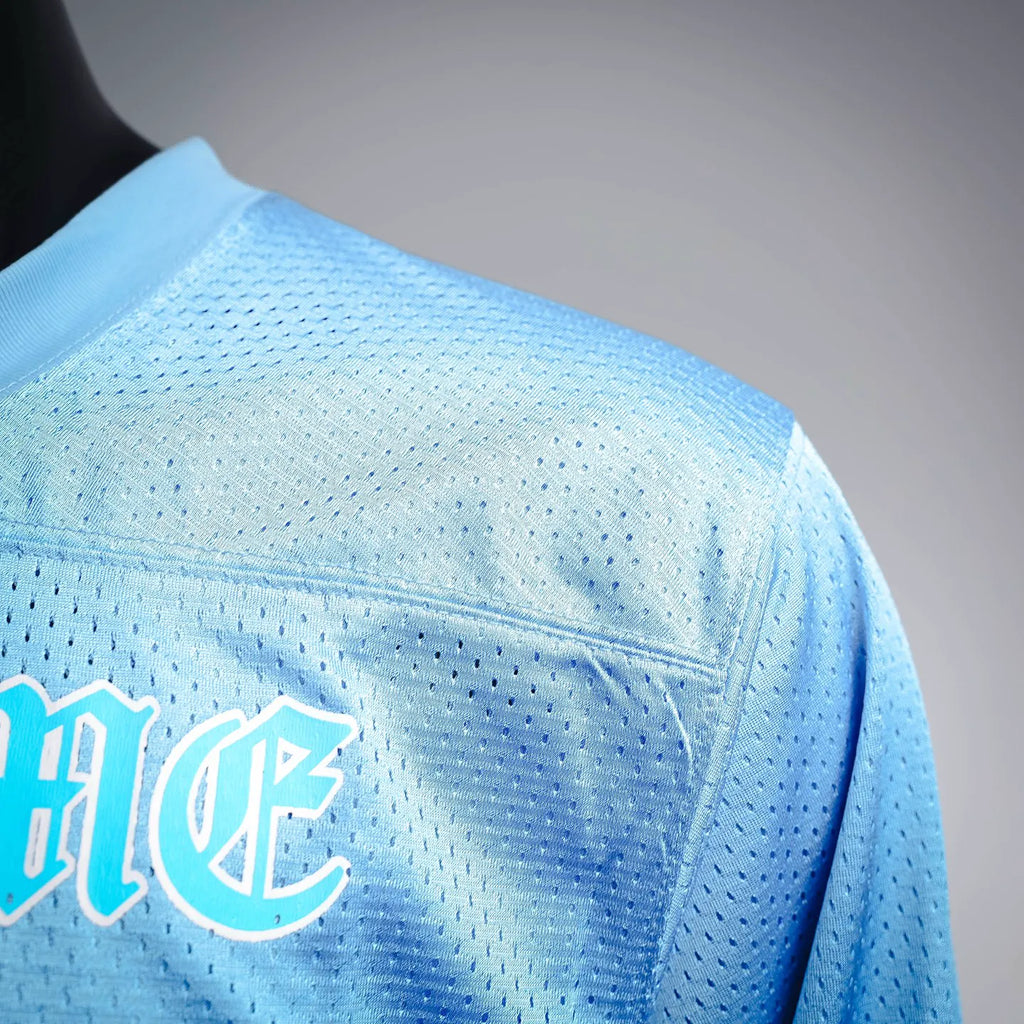 Close-up of light blue jersey back panel with curved seam and partial logo