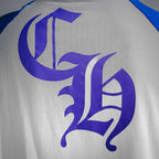 Long-sleeve raglan shirt close-up: large purple monogram graphic on white back