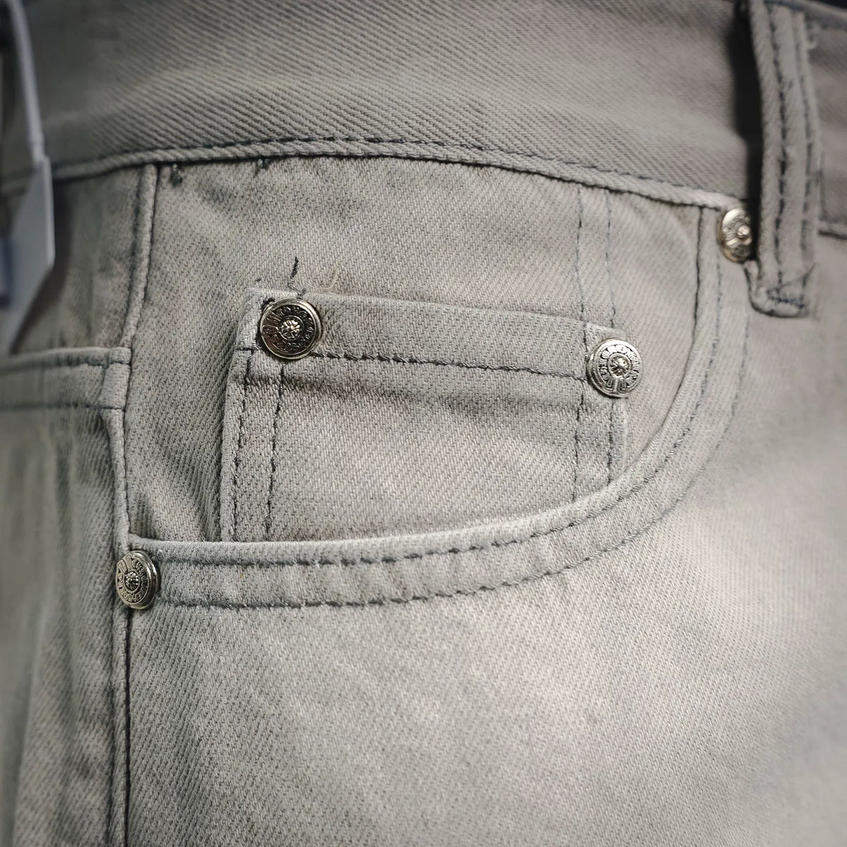 Light gray denim front pocket with metal buttons and curved coin pocket