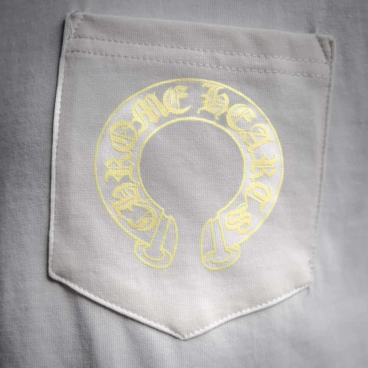 Close-up of white chest pocket with yellow circular logo print