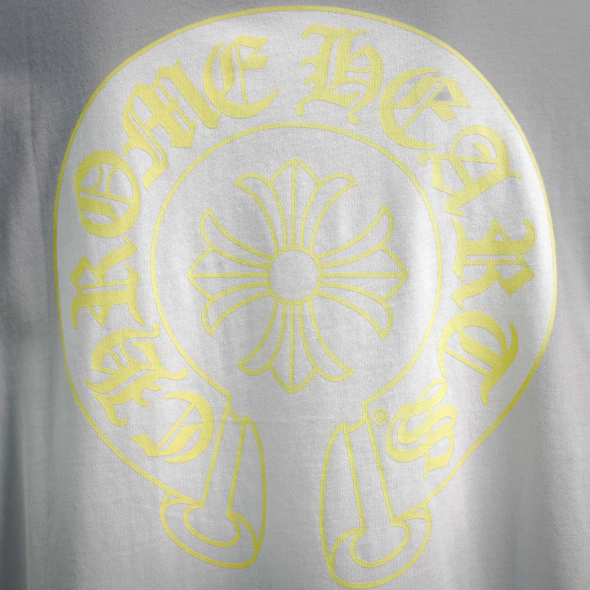 Close-up of yellow circular back graphic with central flower on white T-shirt