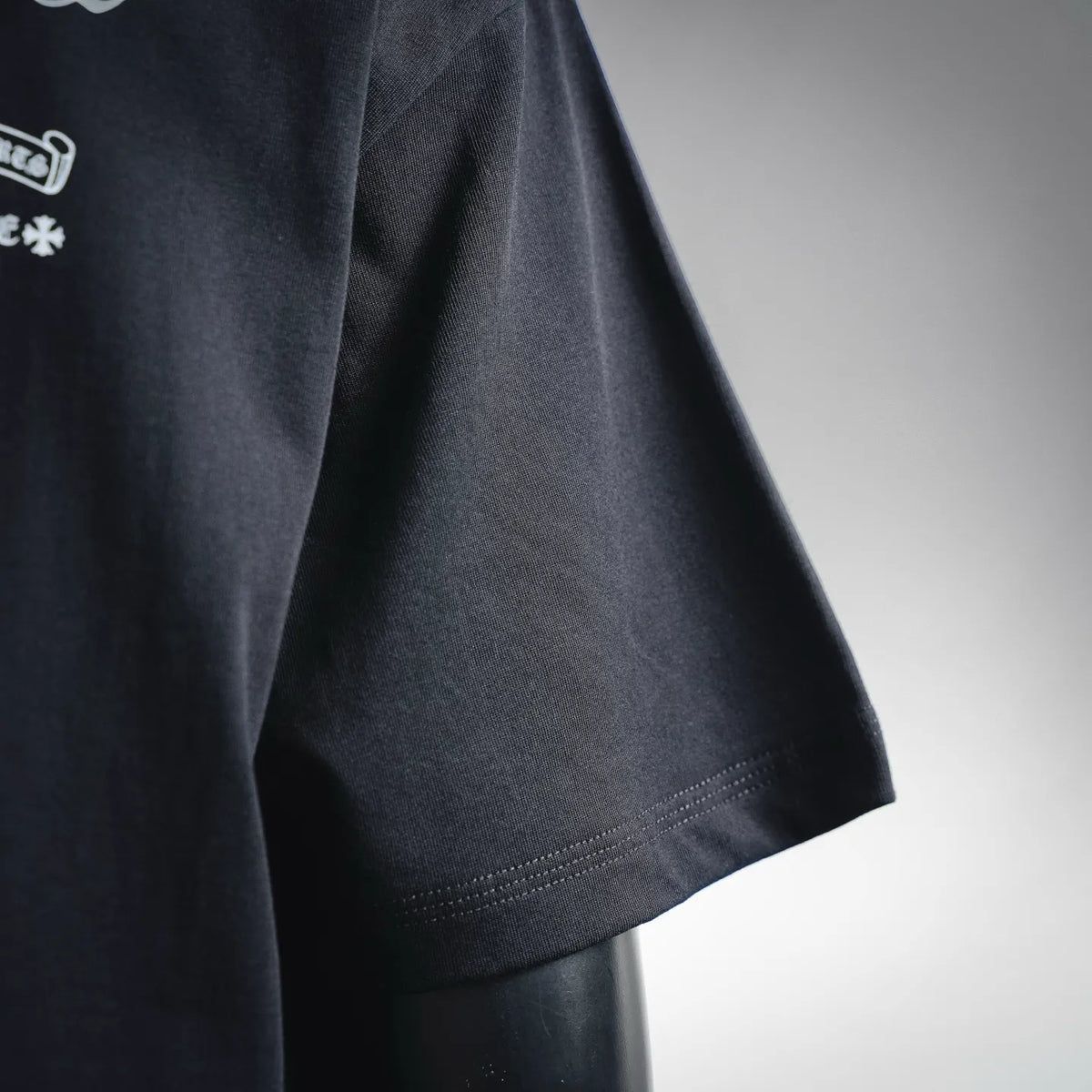 Black T-shirt sleeve and side hem with visible stitching detail