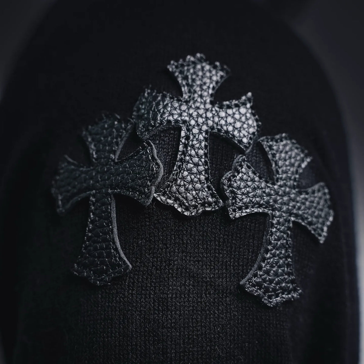 Embroidered black cross-like graphic on a black upper section of the T-shirt
