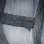 Black fabric label with stamped text on the inside of a light gray T-shirt