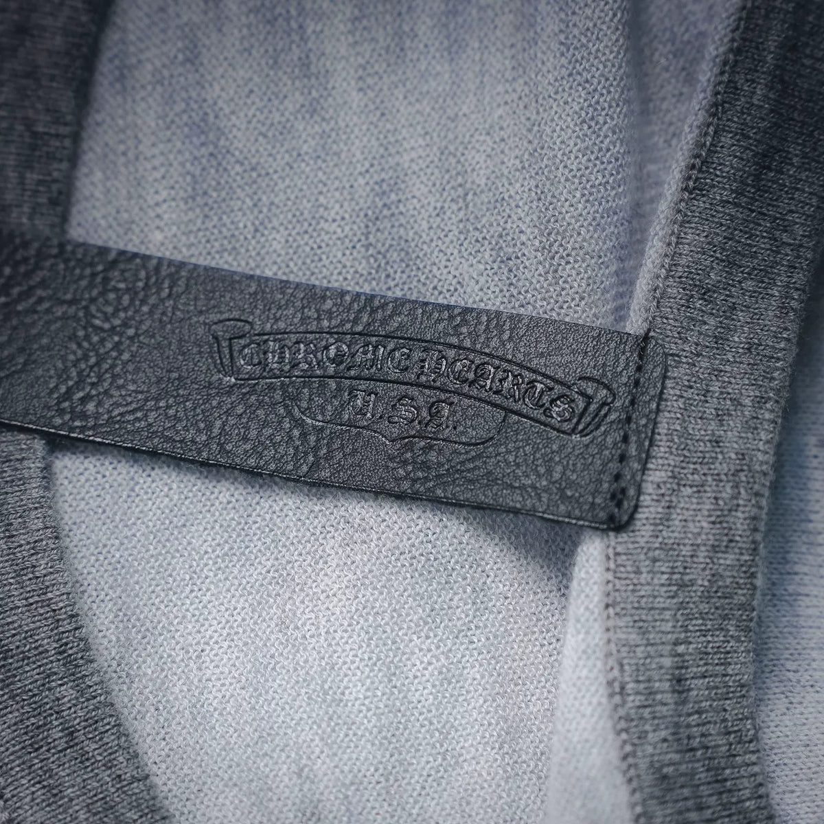 Black fabric label with stamped text on the inside of a light gray T-shirt