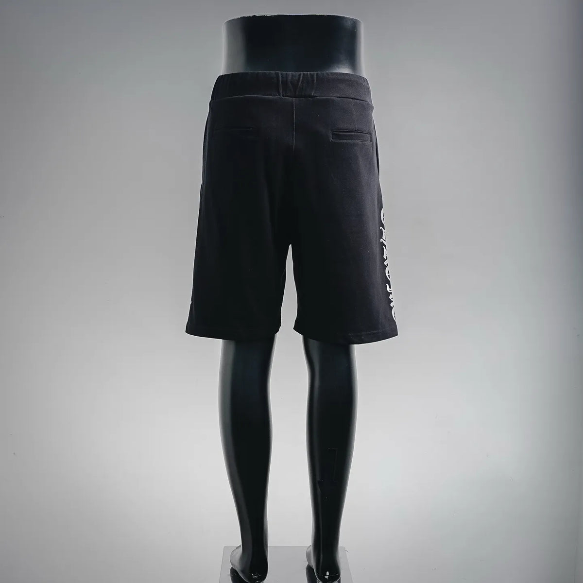 Black drawstring shorts viewed from side with vertical graphic text on leg