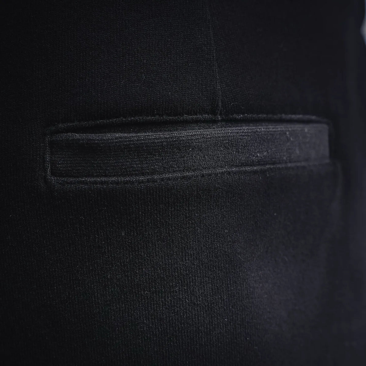 Black shorts fabric close-up showing stitched pocket opening and seam details