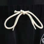 Black elastic waistband with white drawstring cords and metal-tipped ends