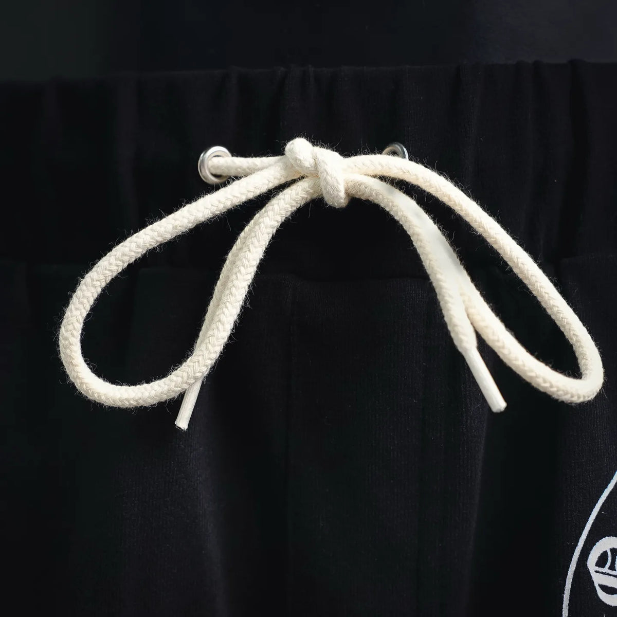 Black elastic waistband with white drawstring cords and metal-tipped ends