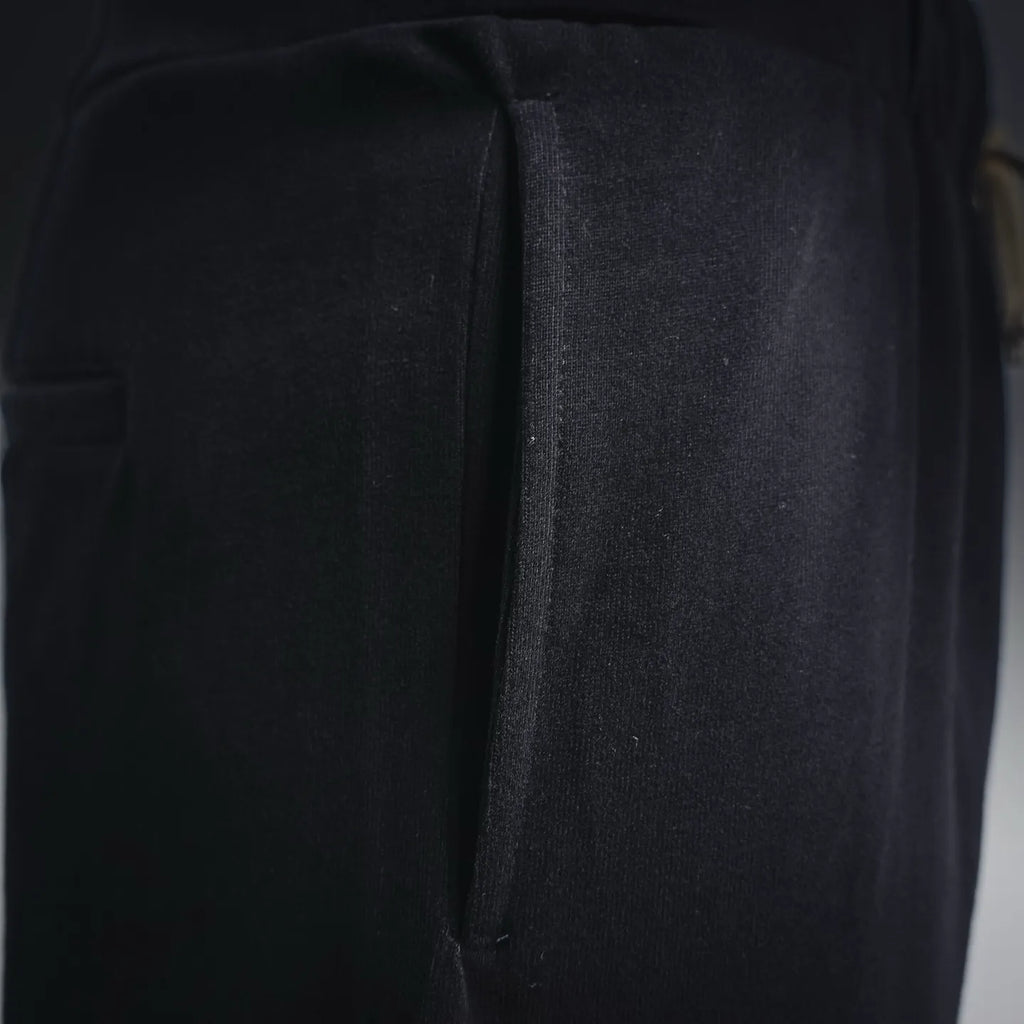 Black shorts close-up showing outer leg seam and relaxed fabric panel