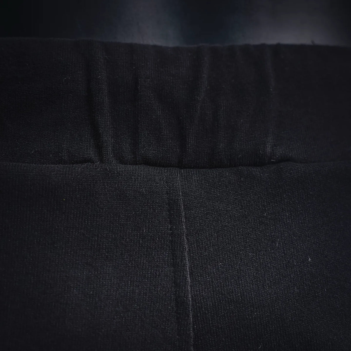 Black shorts waistband close-up with center seam and stitched elastic band