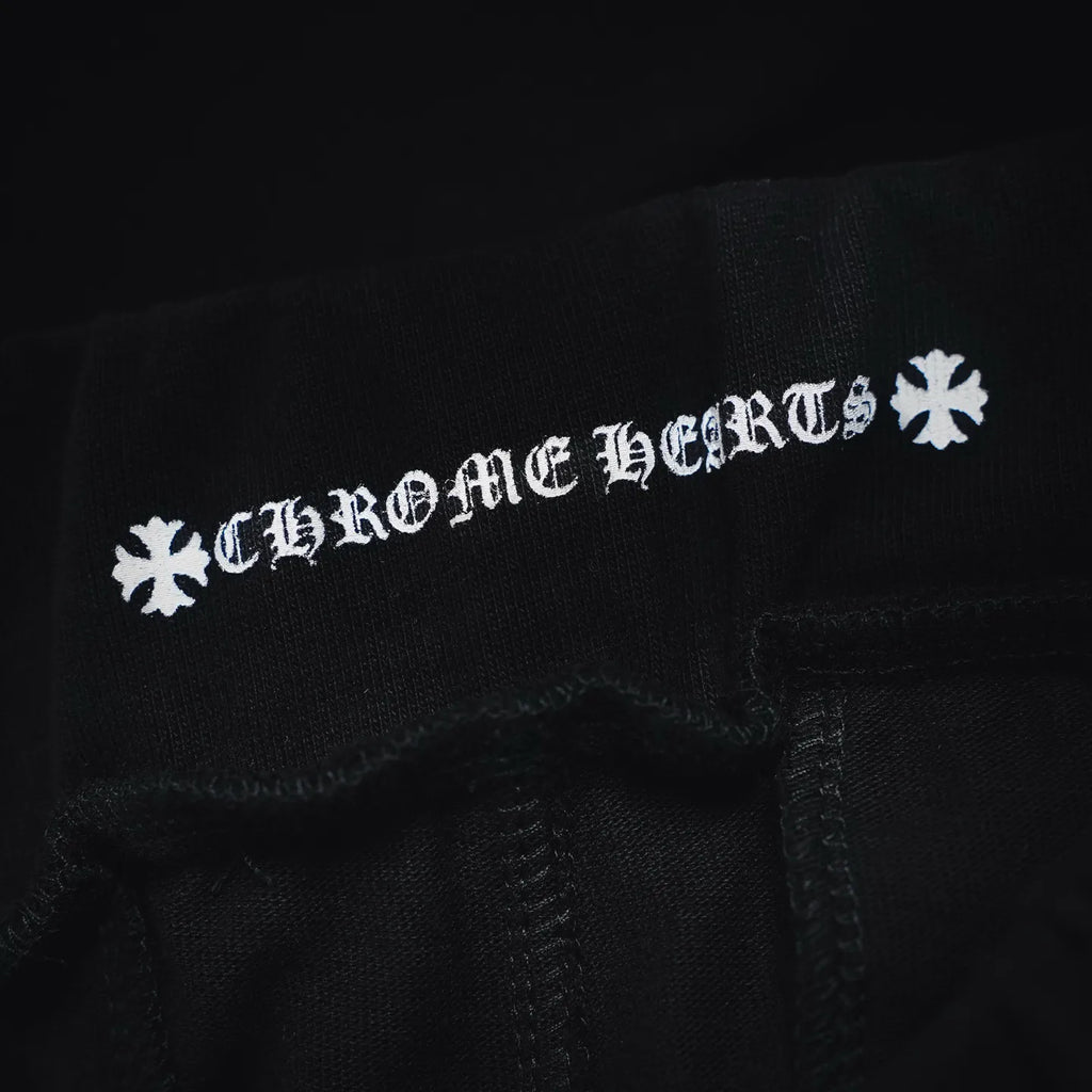Black shorts fabric close-up with white 'Chrome Hearts' style text graphic