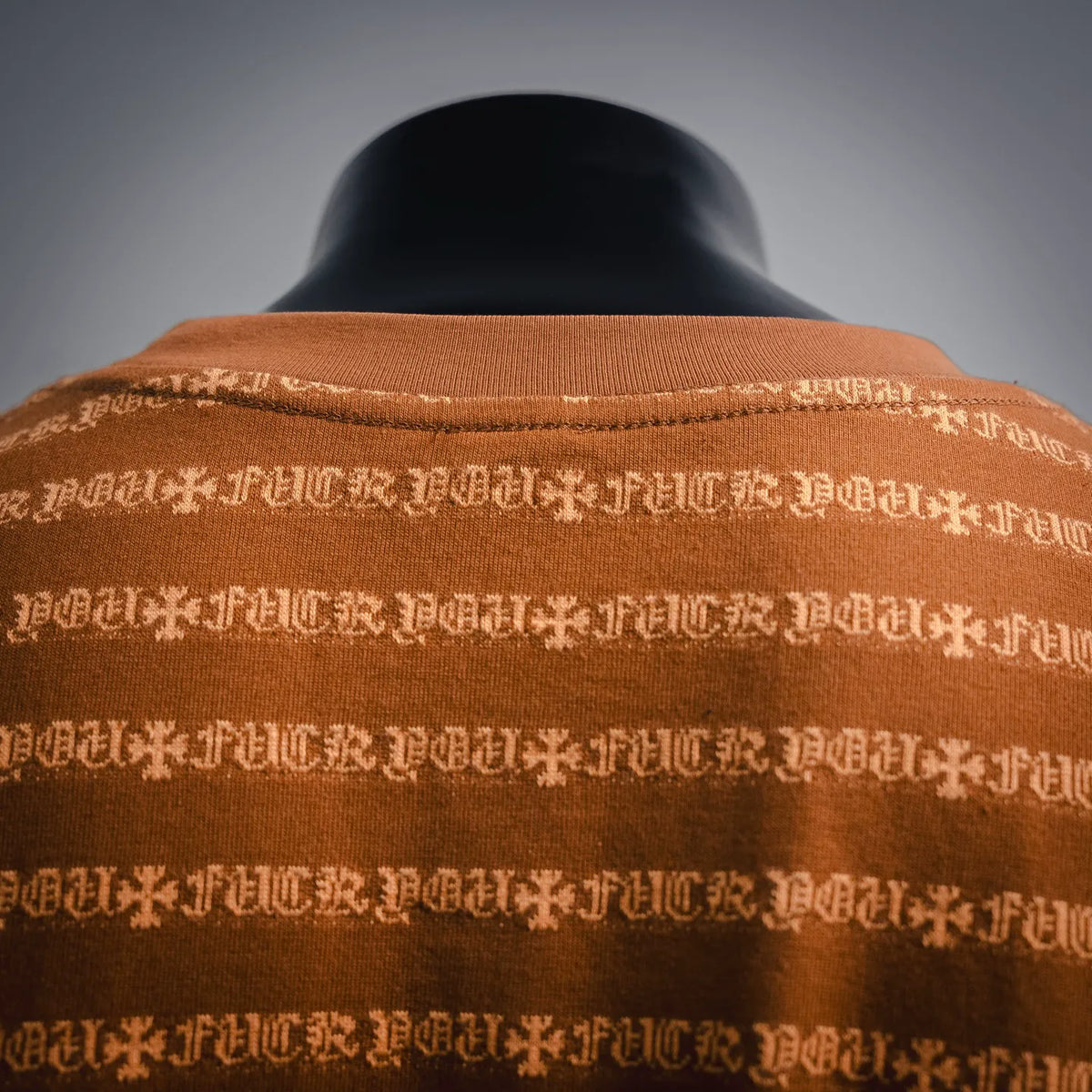 Orange crew-neck T-shirt close-up of collar seam and white logo pattern