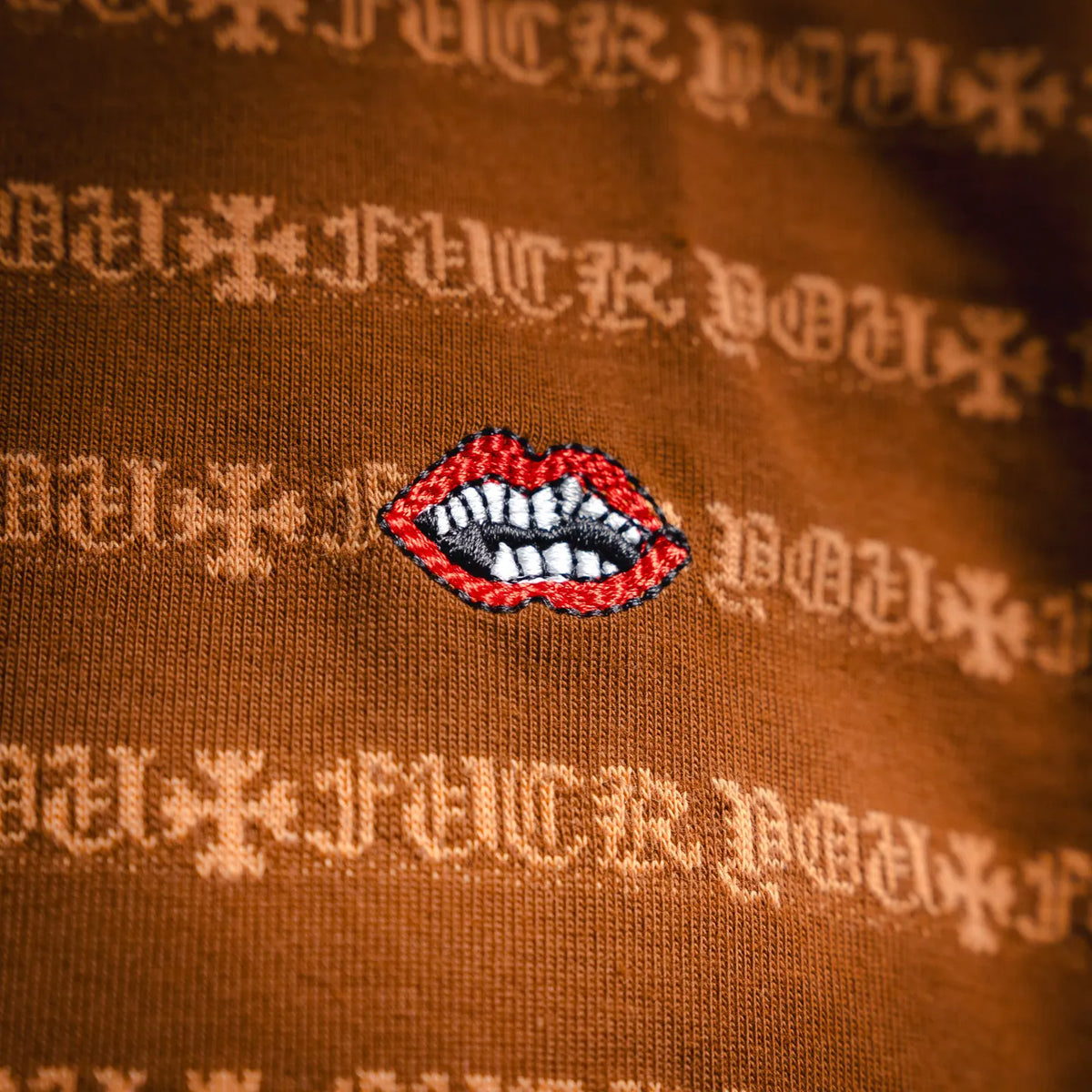 Orange T-shirt with red-and-white lips graphic patch and white logo pattern