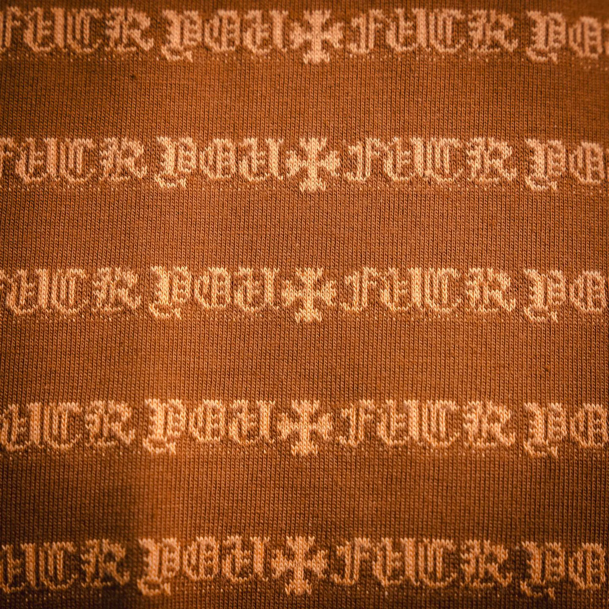 Orange knit T-shirt showing dense white logo pattern across the fabric