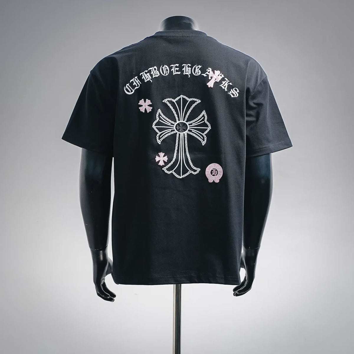 Dark short-sleeve T-shirt with large back cross-style emblem and script text.