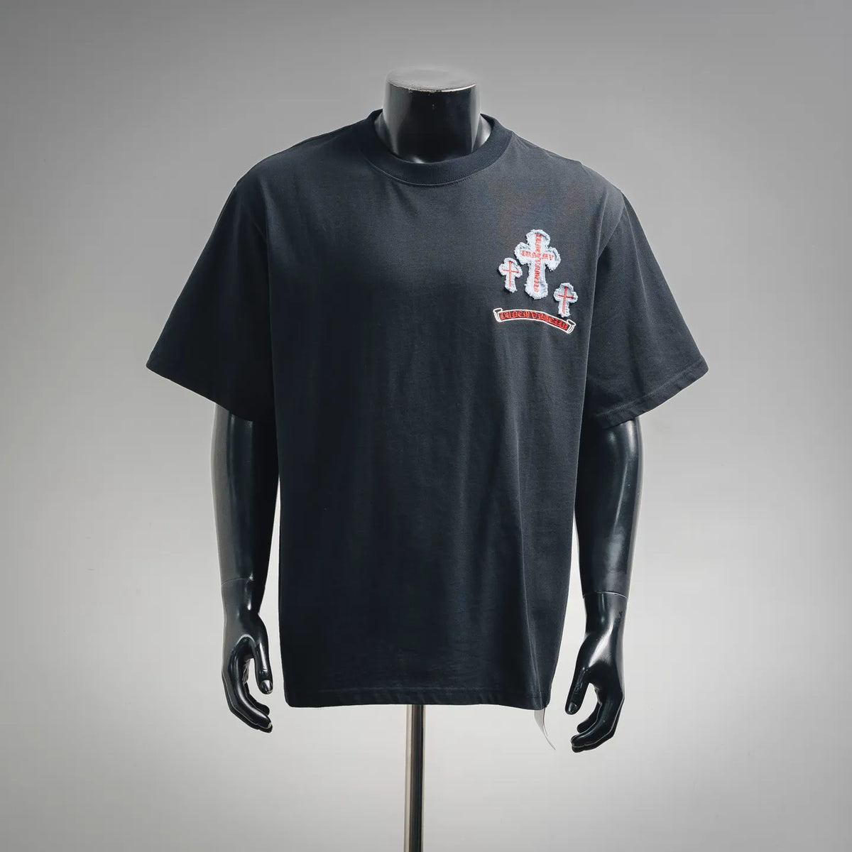 Dark short-sleeve T-shirt with crew neck and chest graphic patch featuring a cross design