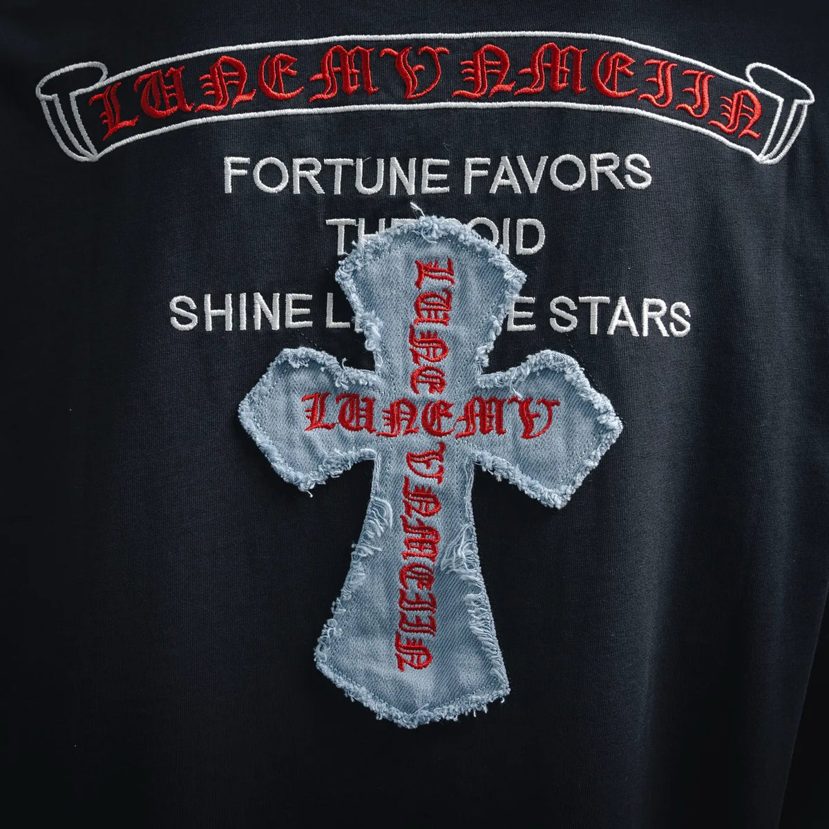 Close-up of T-shirt cross graphic with white applique and red embroidered accents