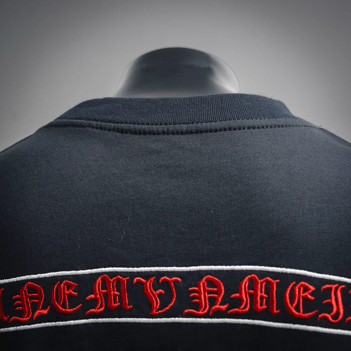T-shirt collar and upper back seam with red embroidered band-style lettering