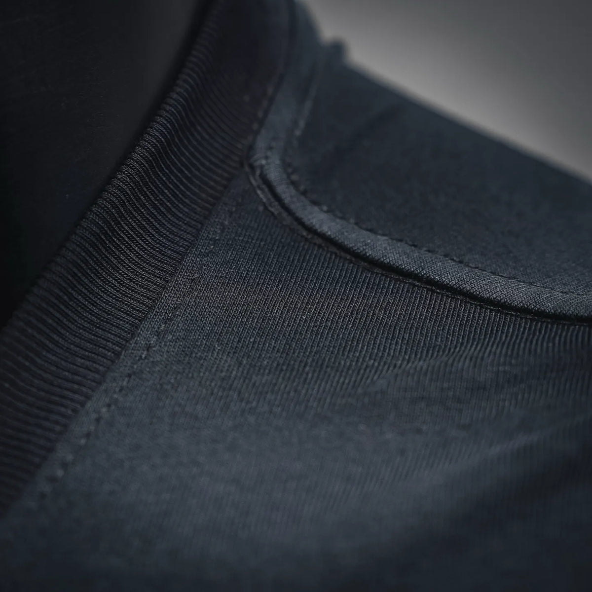 Neckline seam and ribbed trim close-up on dark long-sleeve crewneck T-shirt