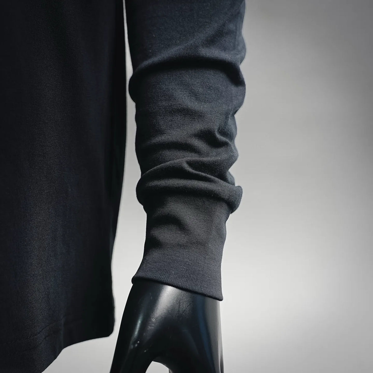 Dark long-sleeve shirt sleeve cuff close-up with gathered fabric at hem