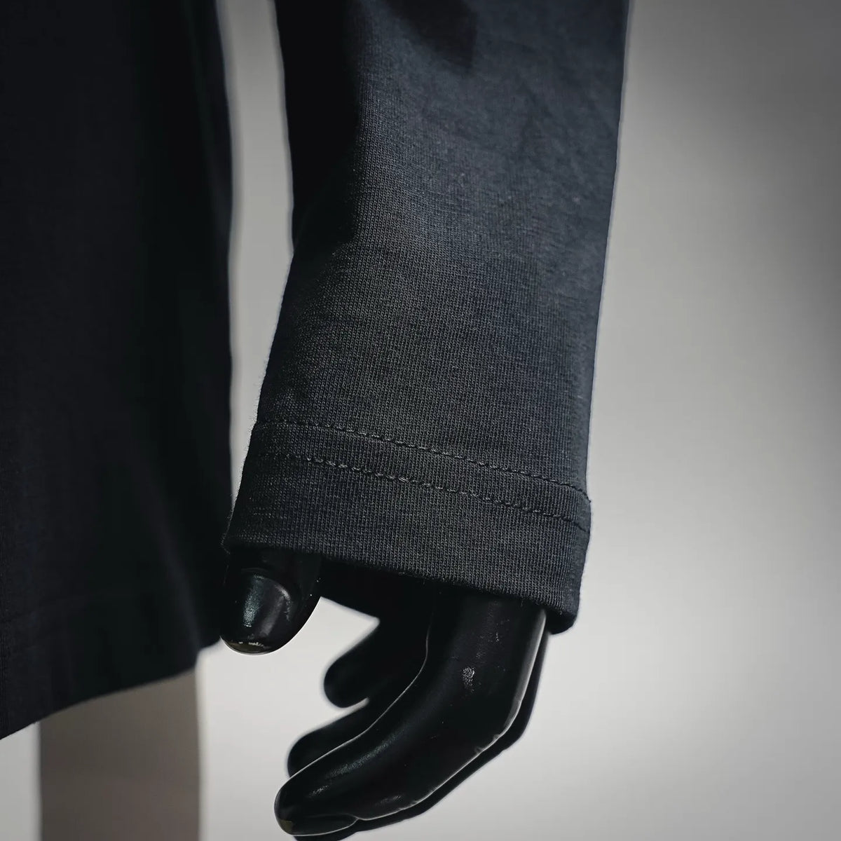 Black long-sleeve T-shirt sleeve cuff close-up with stitched hem