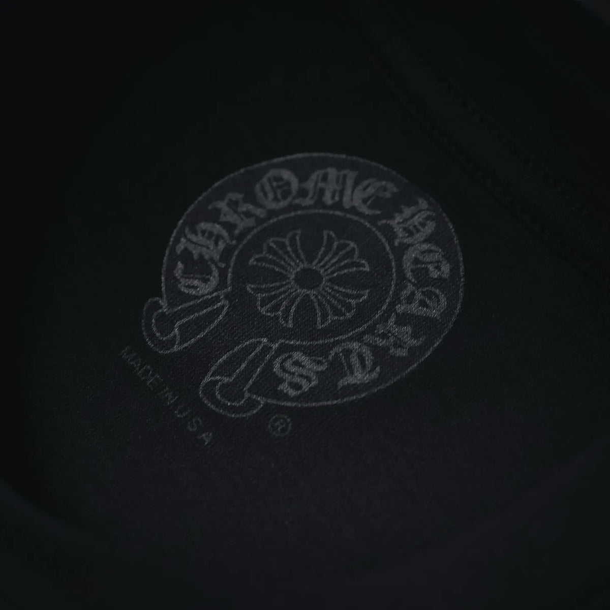 Embossed tonal logo on dark T-shirt fabric, circular head graphic