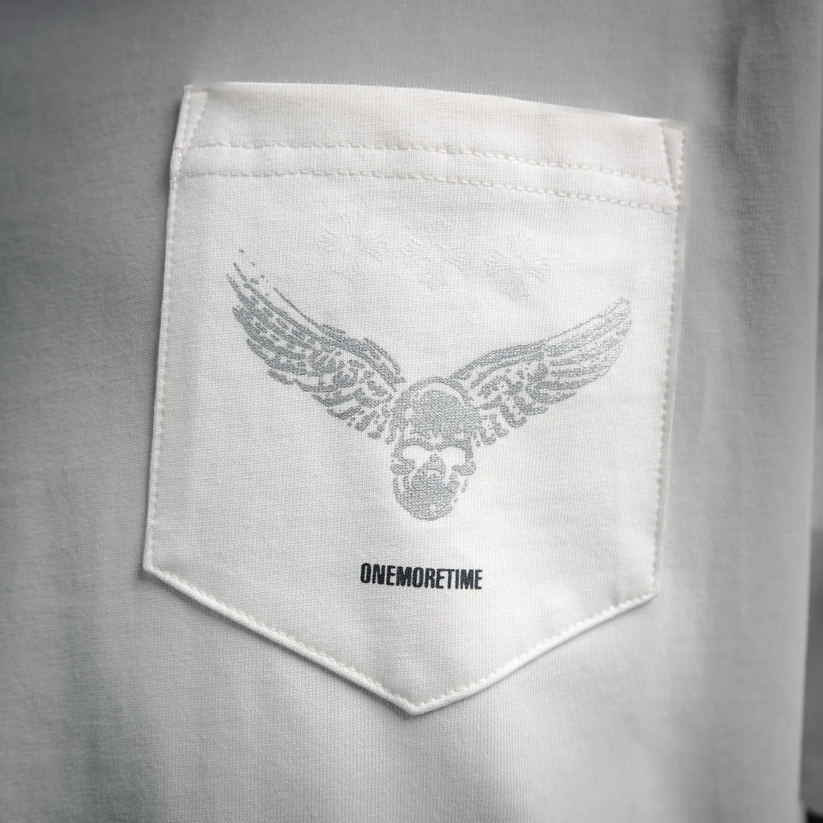 White chest pocket with wing graphic and "ONEMORETIME" text