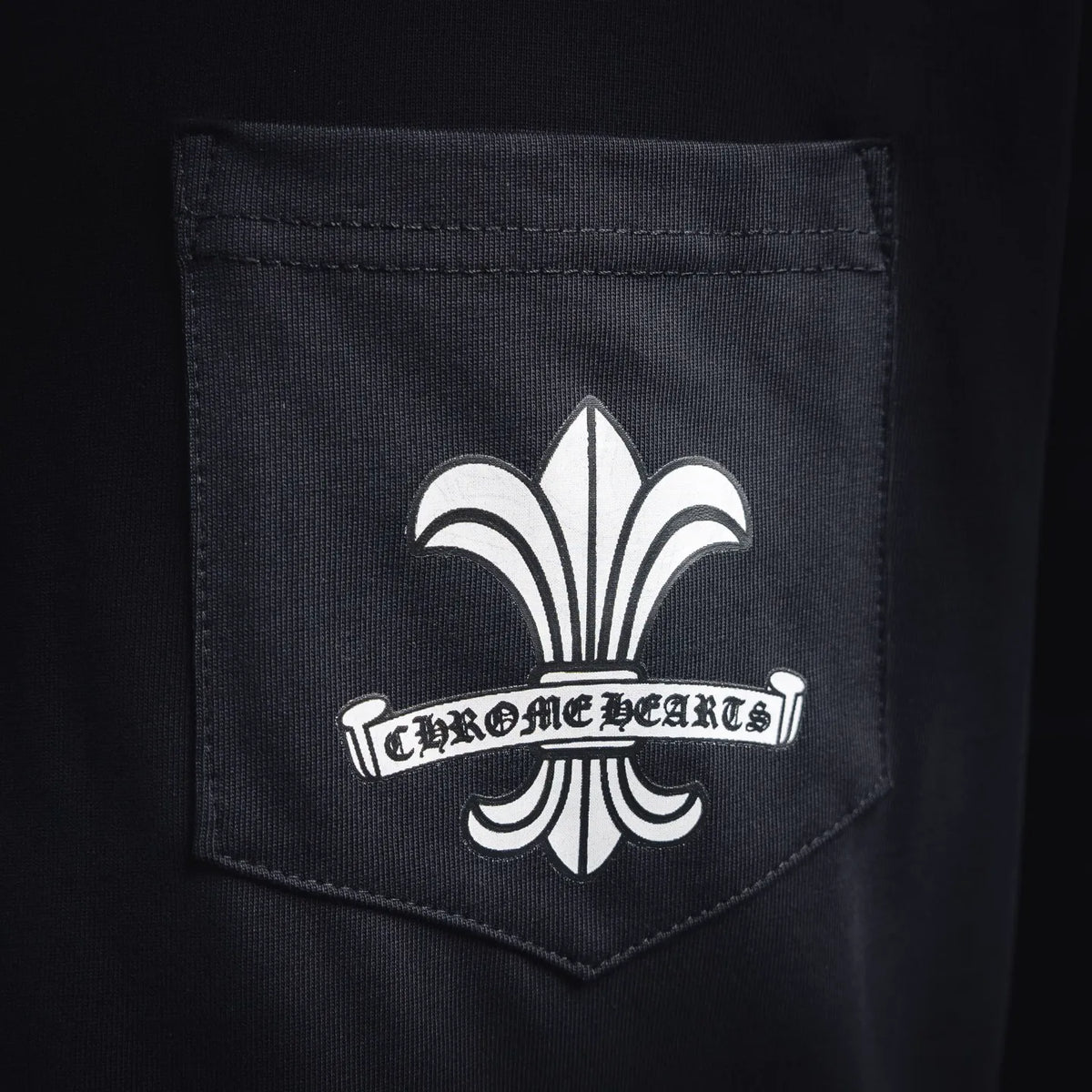 Black T-shirt pocket with white fleur-de-lis logo emblem