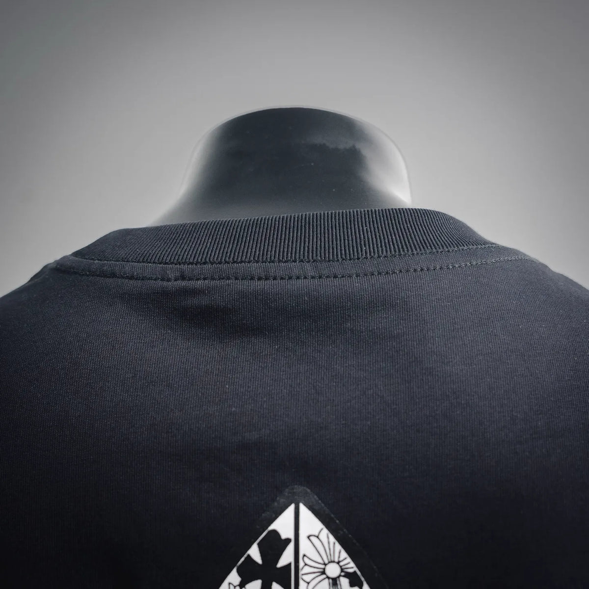 Black T-shirt back neckline with ribbed collar and small fleur-de-lis top graphic