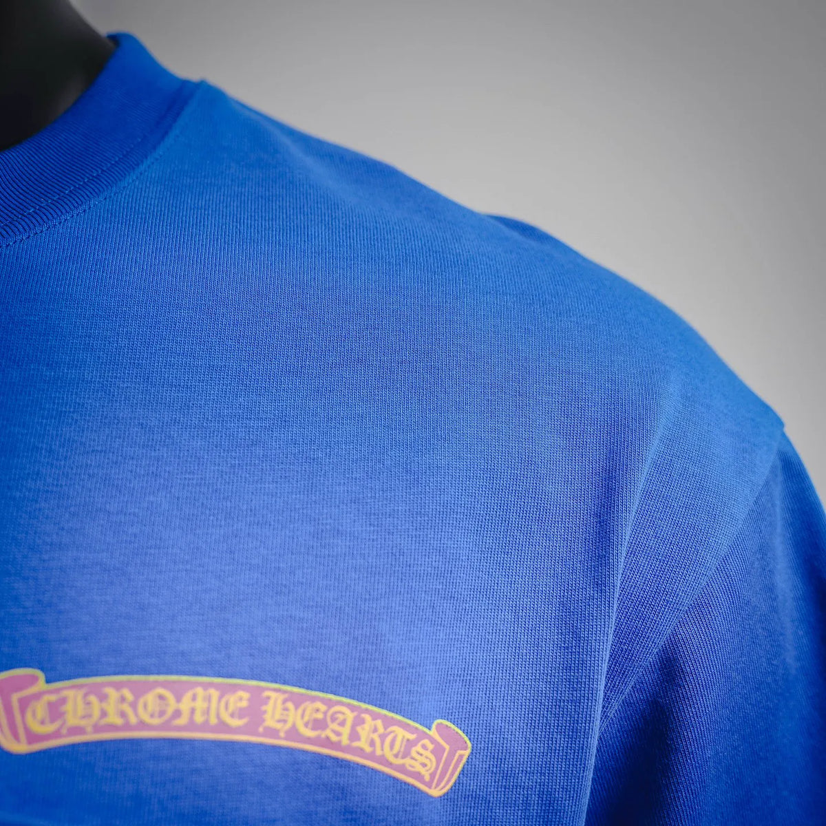 Blue T-shirt close-up of arched back logo embroidery on upper back