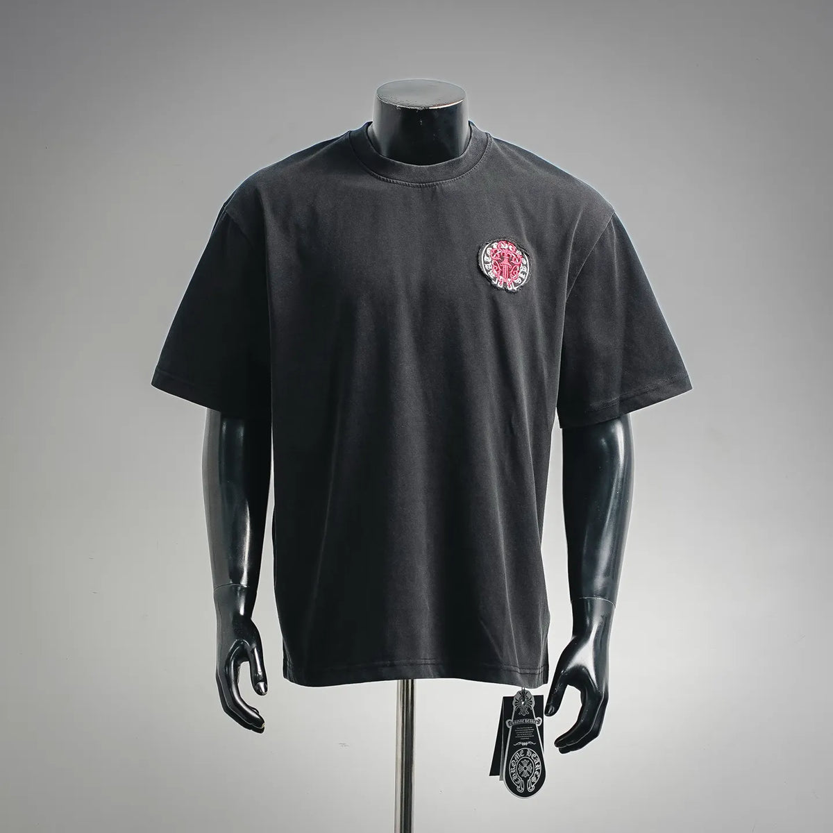 Black crewneck short-sleeve T-shirt with small red-and-white crest patch on chest
