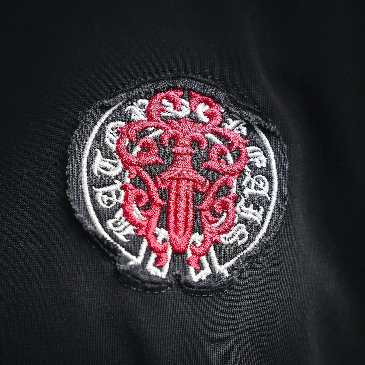 Black T-shirt chest patch with red-and-white circular crest embroidery