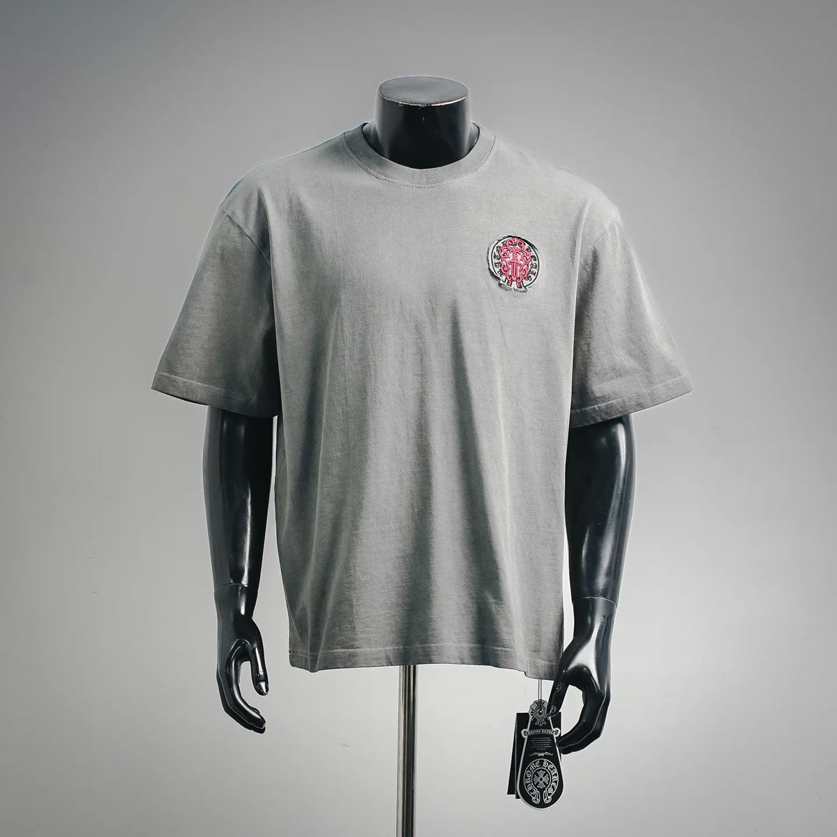 Gray short-sleeve T-shirt with small red-and-white crest patch on left chest.