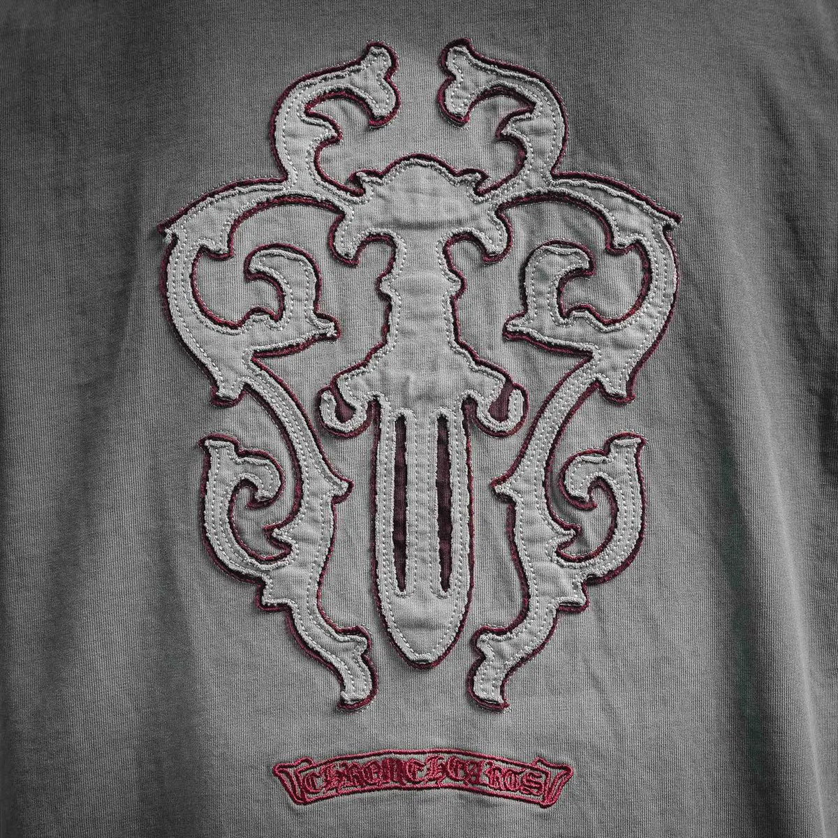 Large red-and-white crest graphic with stitched border on gray T-shirt.