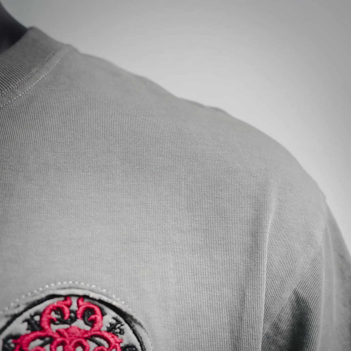 Gray T-shirt sleeve and shoulder seam with stitched edge detail.