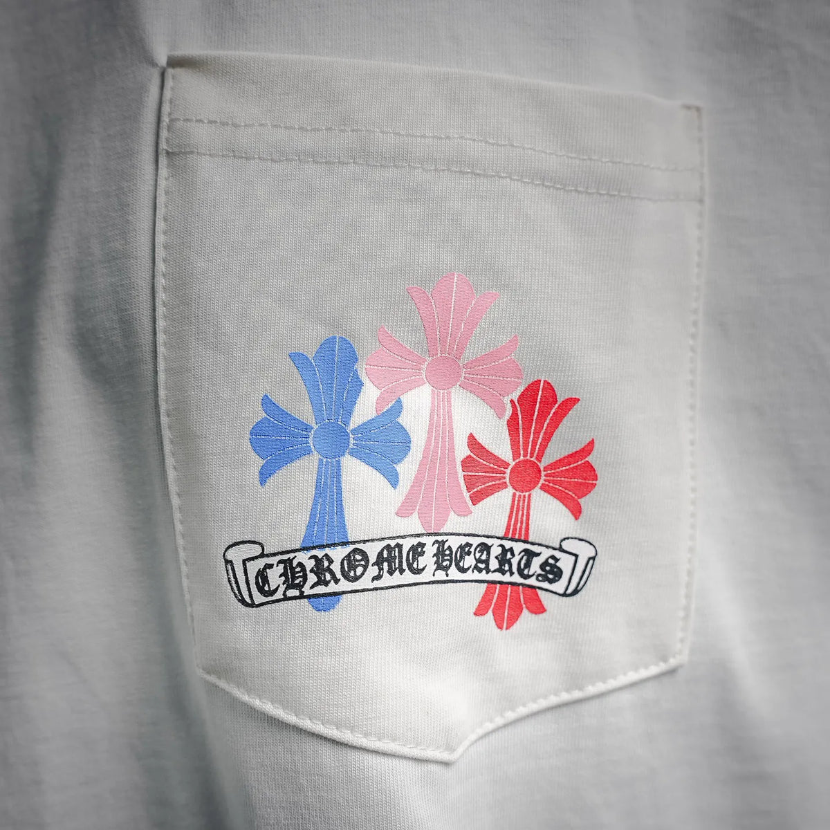 White T-shirt chest pocket with multicolor flower graphic and ribbon-style text