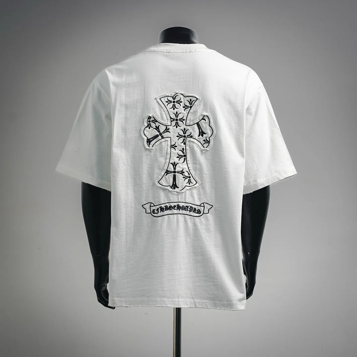White short-sleeve T-shirt with large black cross graphic and banner on back.