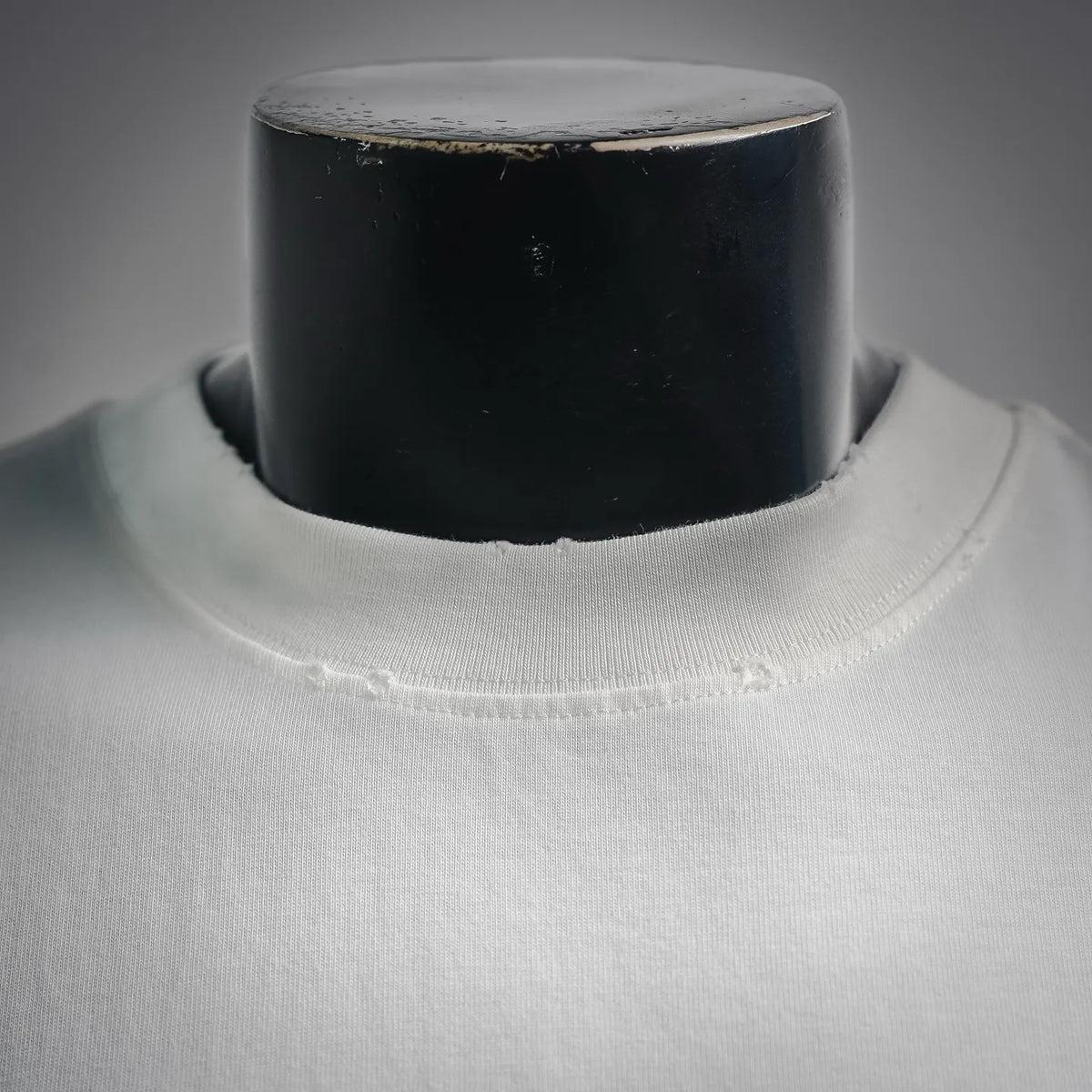 White T-shirt neckline close-up with ribbed collar and visible stitching.