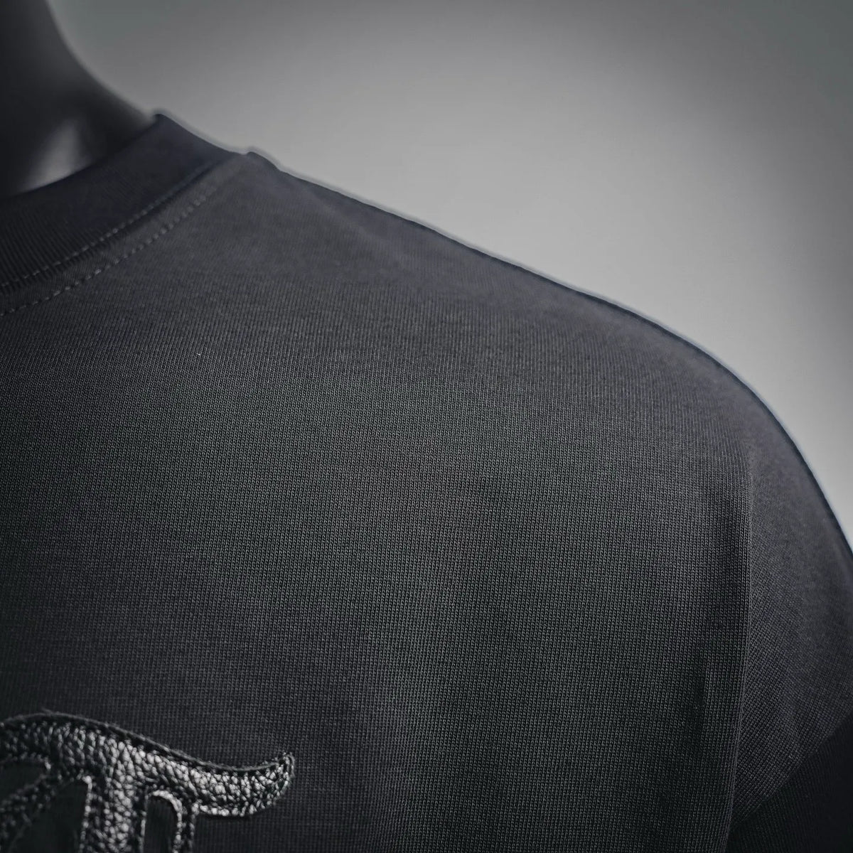 Black T-shirt shoulder close-up with visible knit texture and stitching