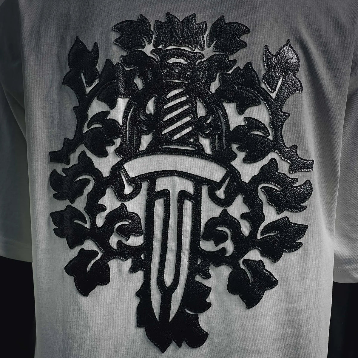 Close-up of black embroidered-style emblem on white T-shirt front