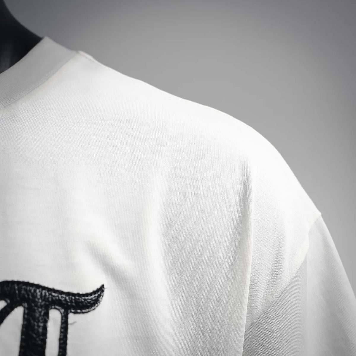 White T-shirt sleeve and shoulder seam with partial black chest graphic
