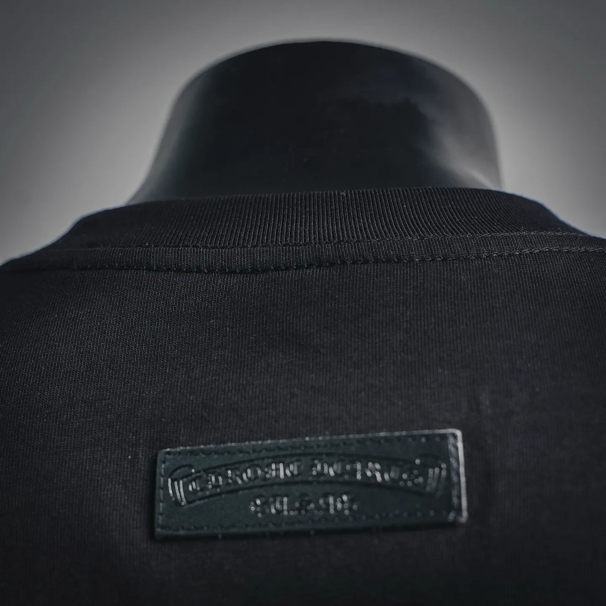 Black T-shirt neckline with embroidered brand tag inside collar