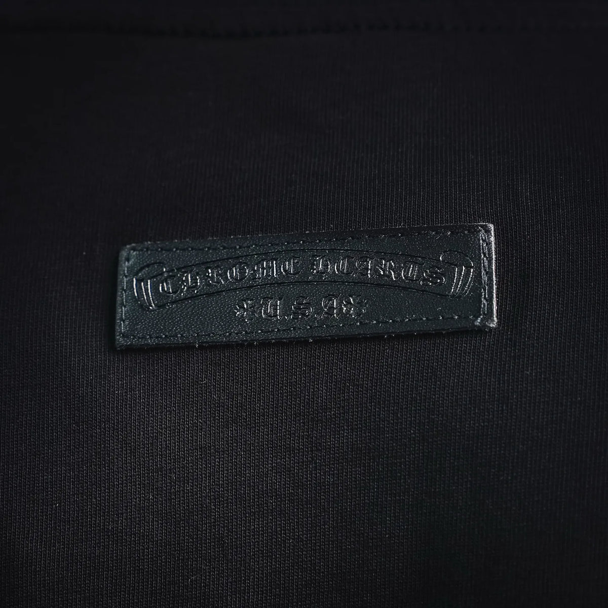 Close-up of rectangular embroidered neck brand label on a black T-shirt